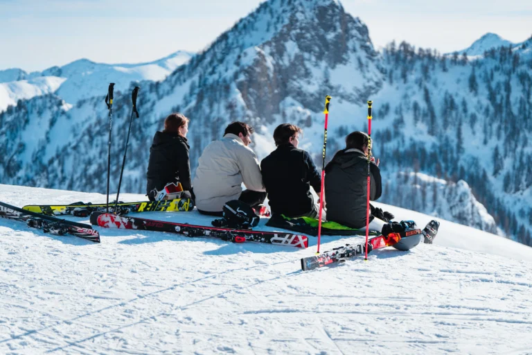 Sciatori seduti sulla neve davanti al panorama delle montagne.